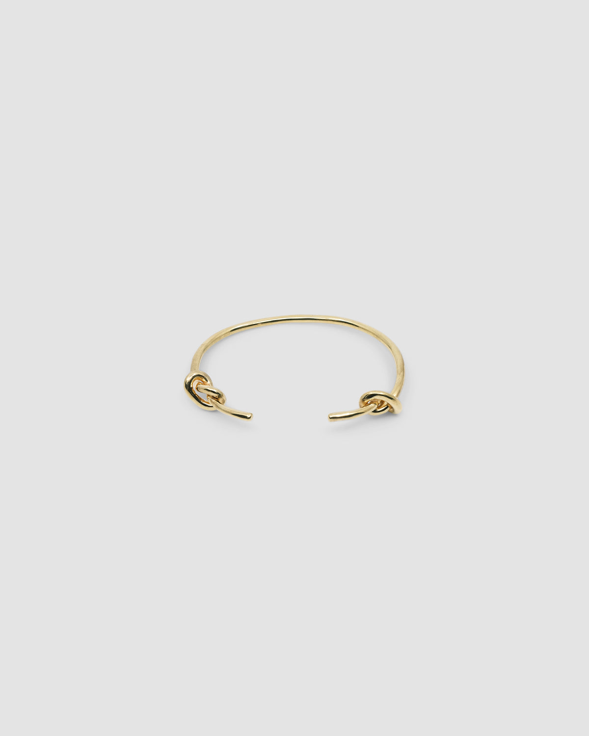 Gold open style bangle with two knots at the end