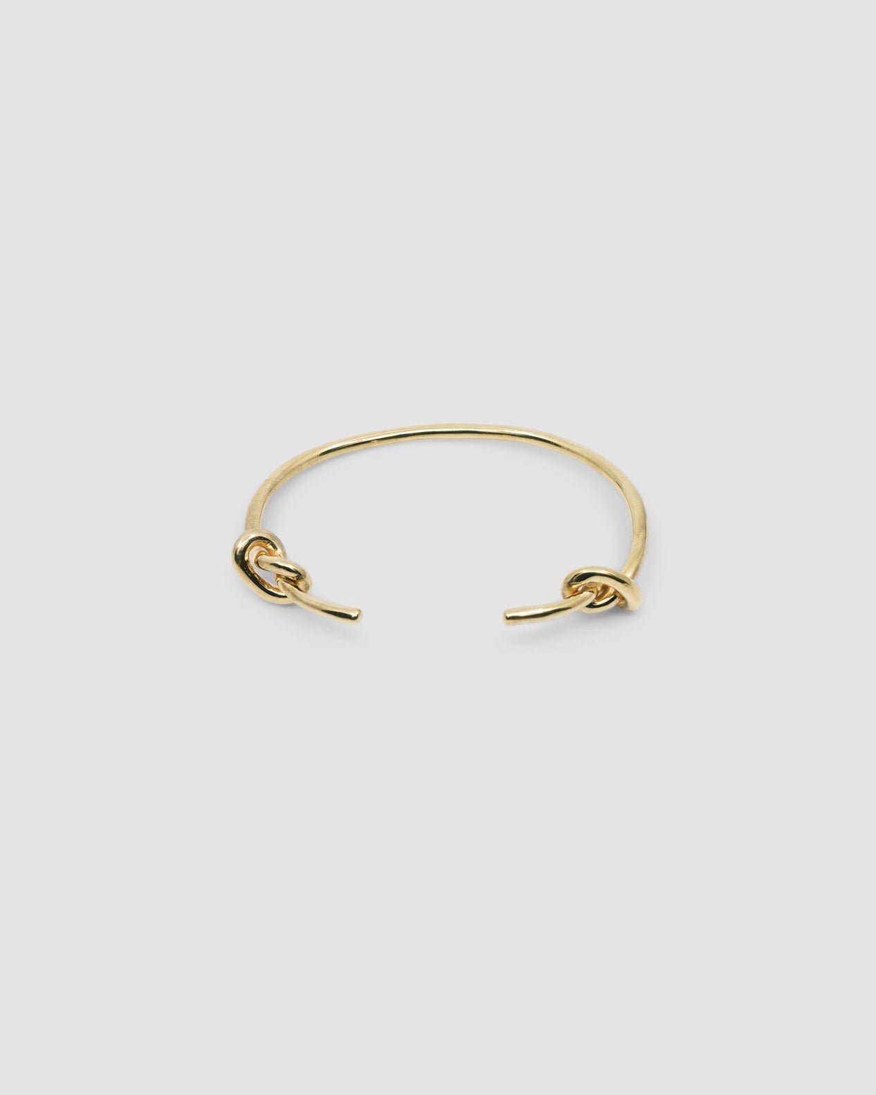 Gold open style bangle with two knots at the end