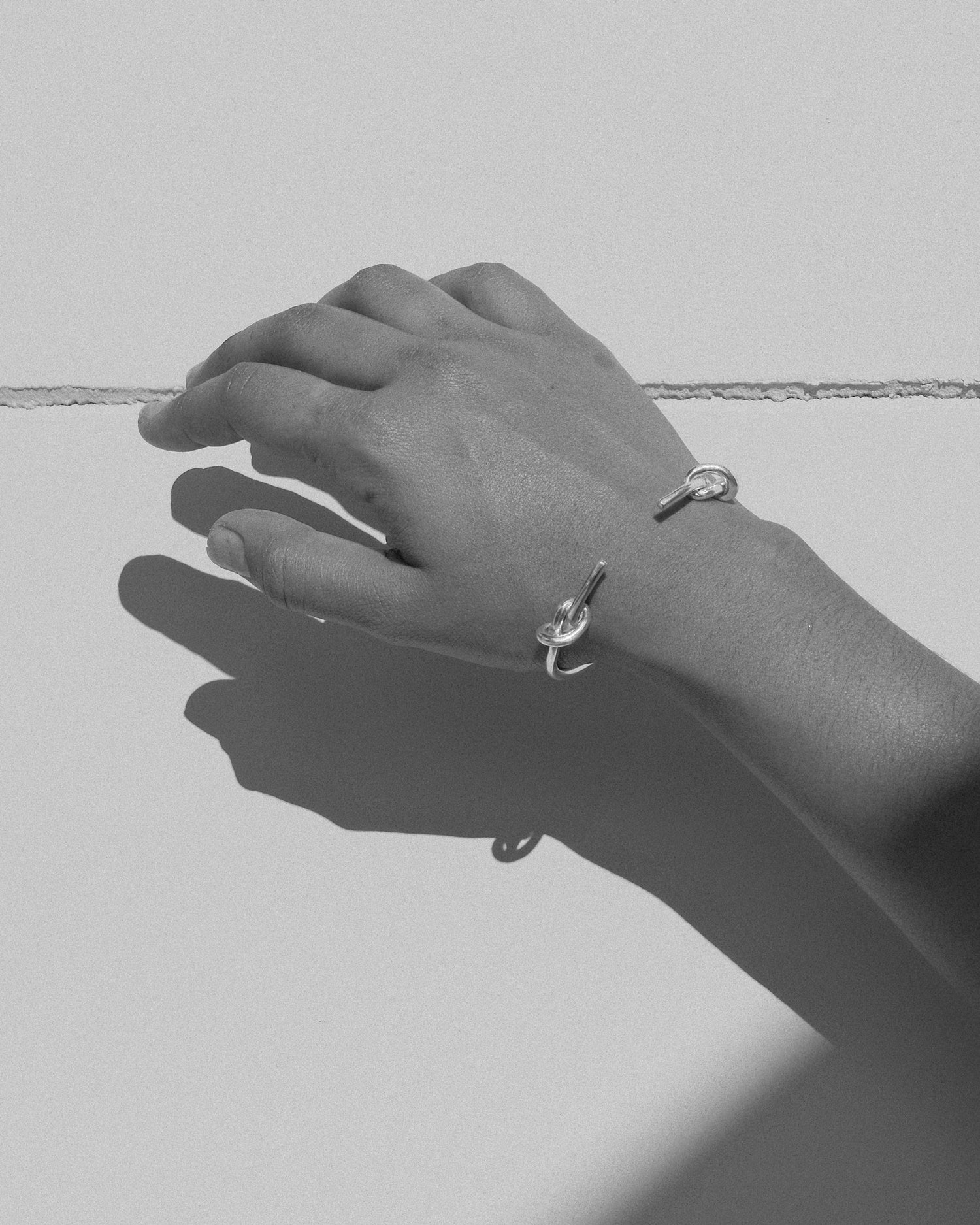 a open cuff bracelet with knots either side sits on an arm