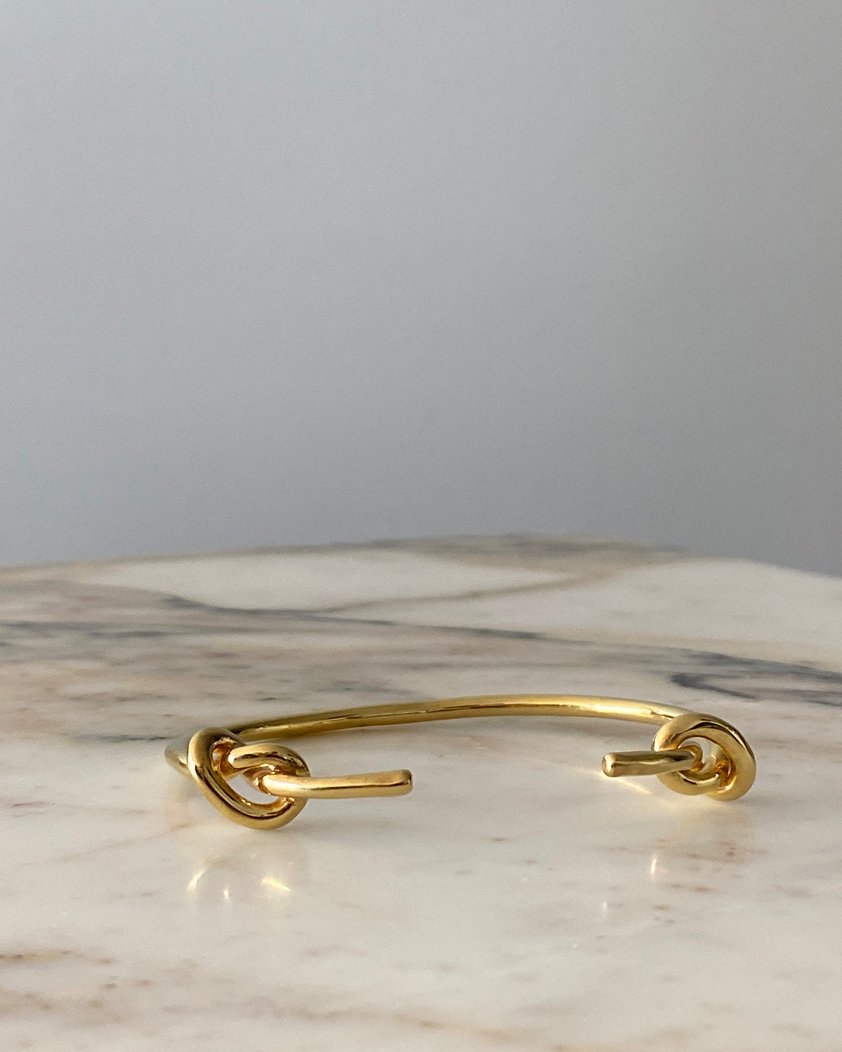 Gold open cuff bracelet with knots at the end