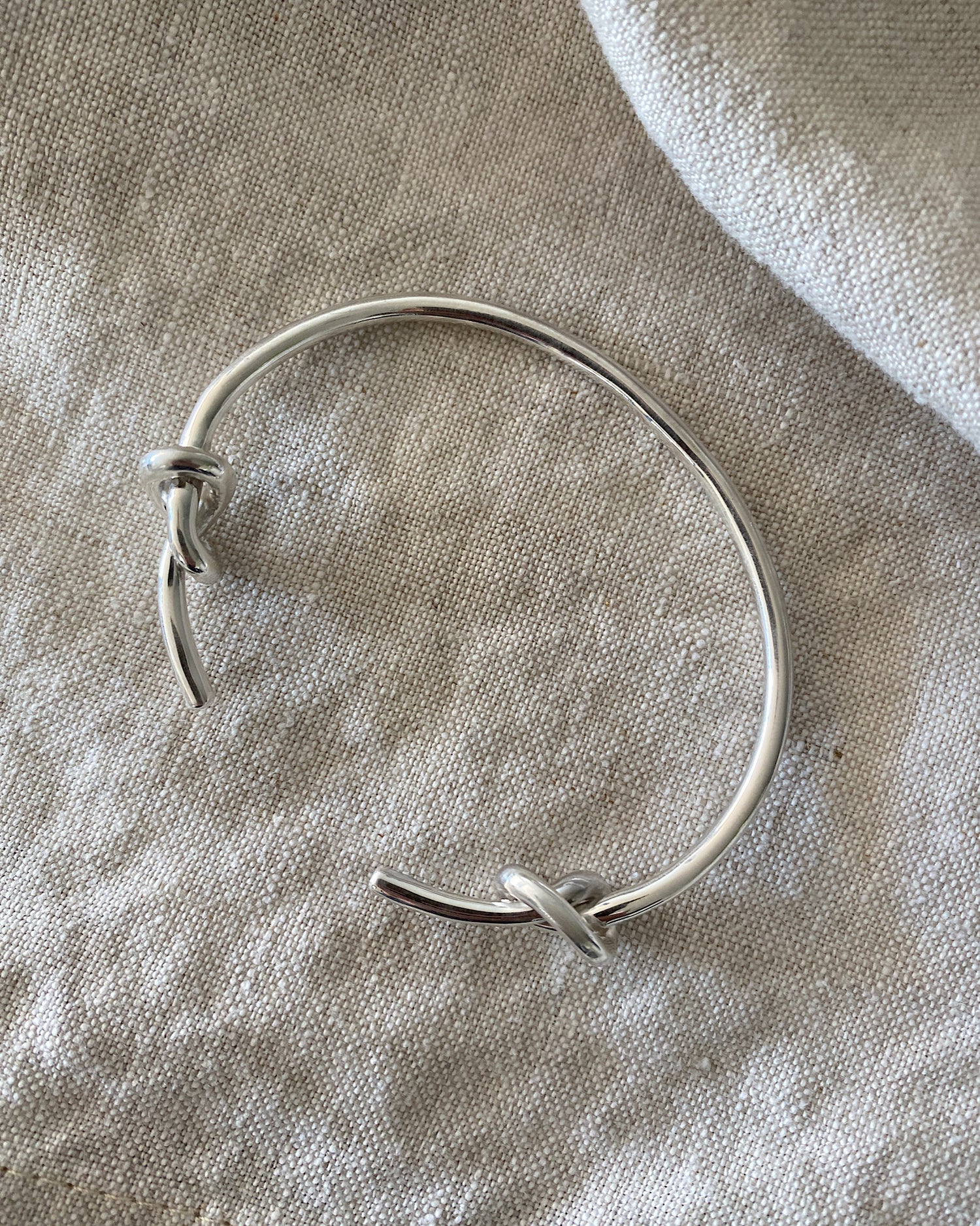 Silver open style bangle with two knots at the end
