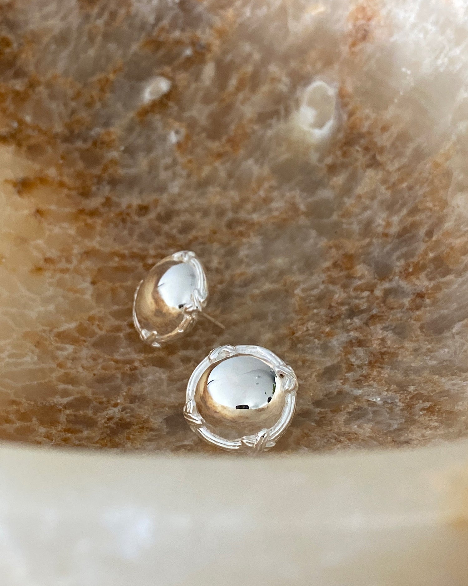 simple round silver studs that features a cross border sit in a textured bowl