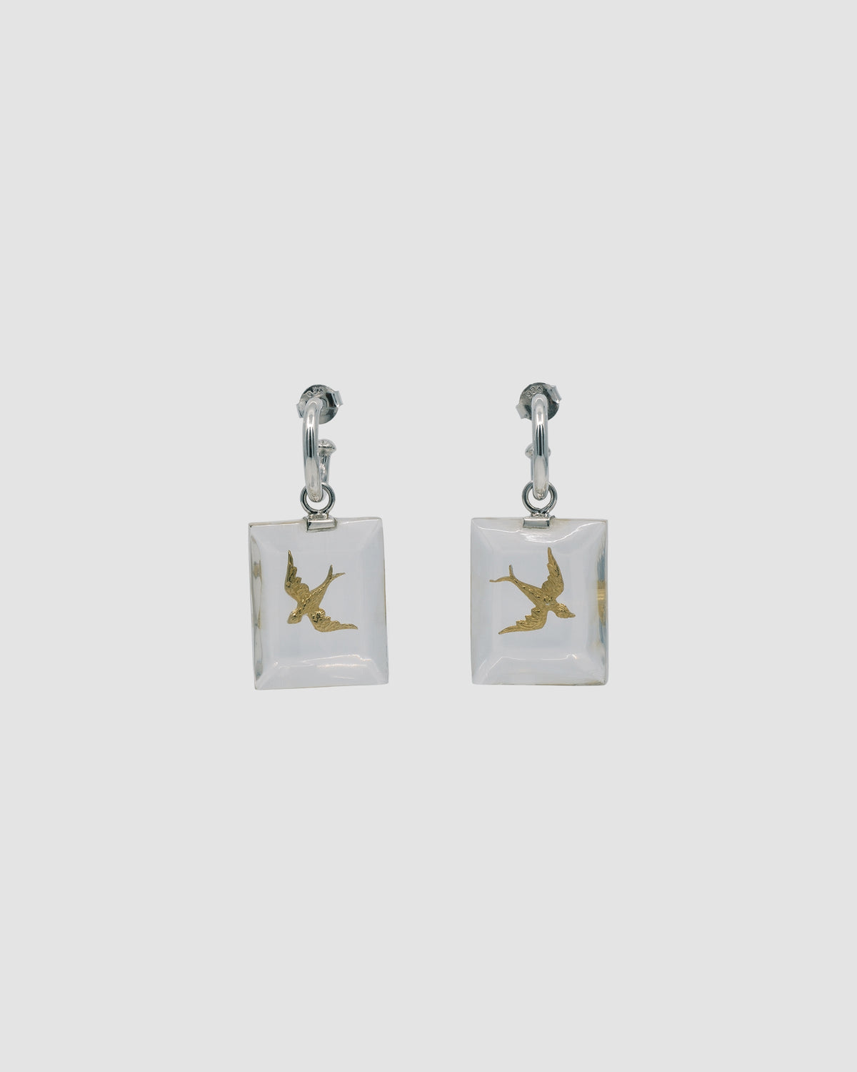 gold swallow bird charms are encased in a clear resin rectangle and dangle from a silver hoop earring