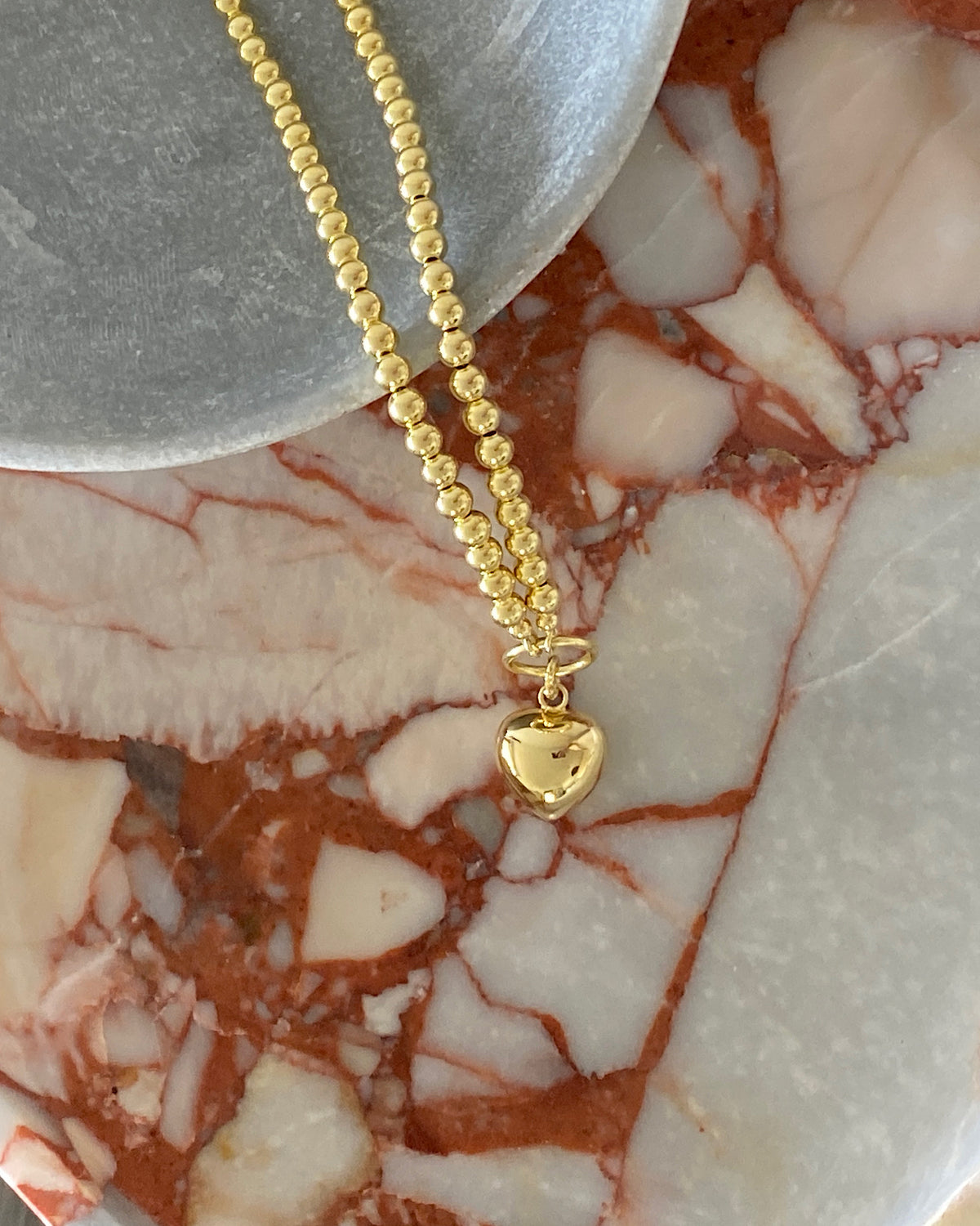 a gold charm necklace with a heart charm attached