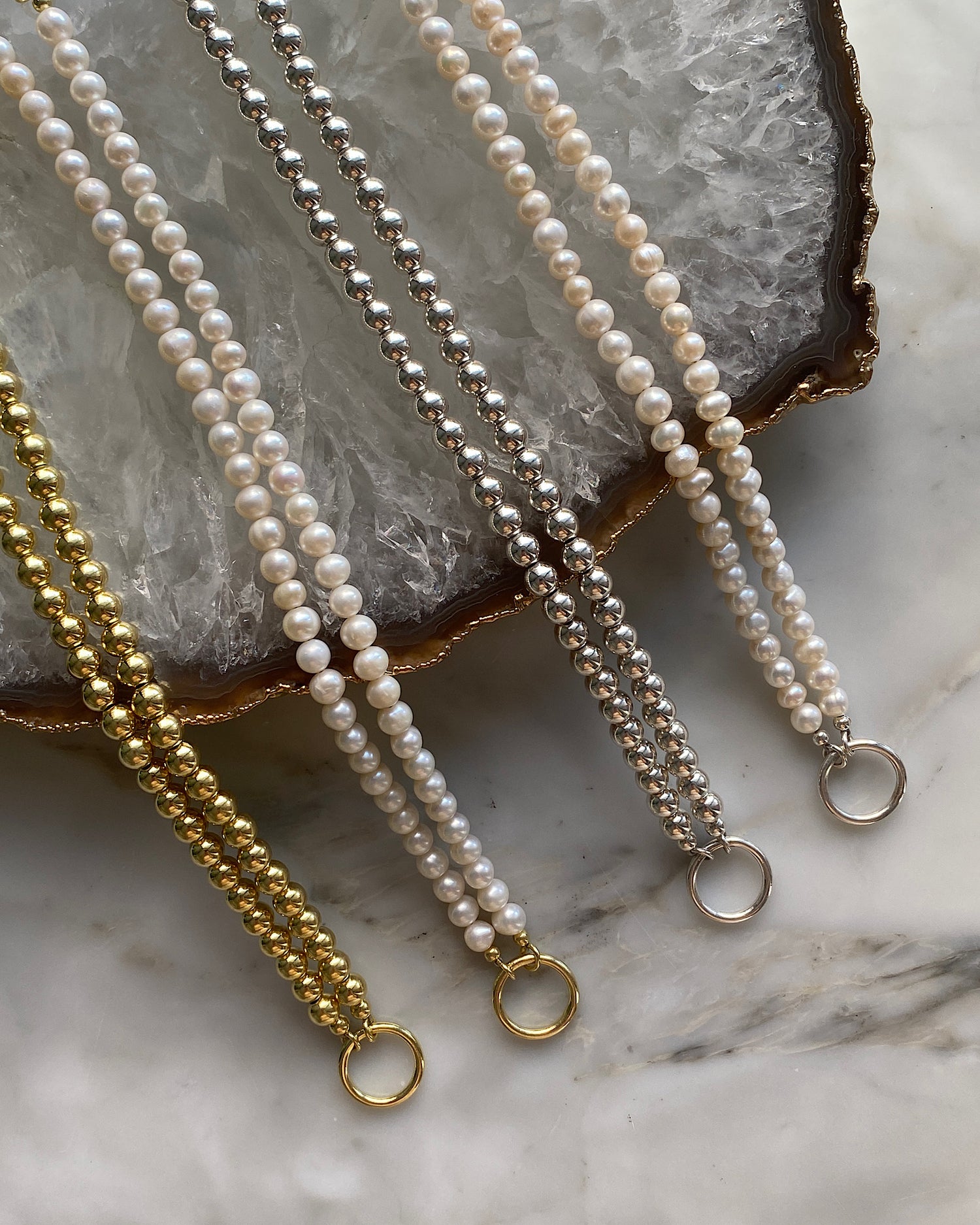 a selection of pearl and metallic ball necklaces with a central ring for hanging charms