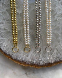 a selection of pearl and metallic ball necklaces with a central ring for hanging charms