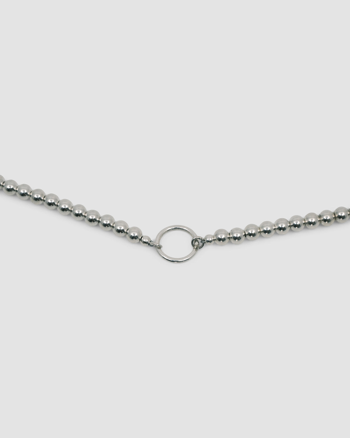 detail of a silver ball necklace with a central ring