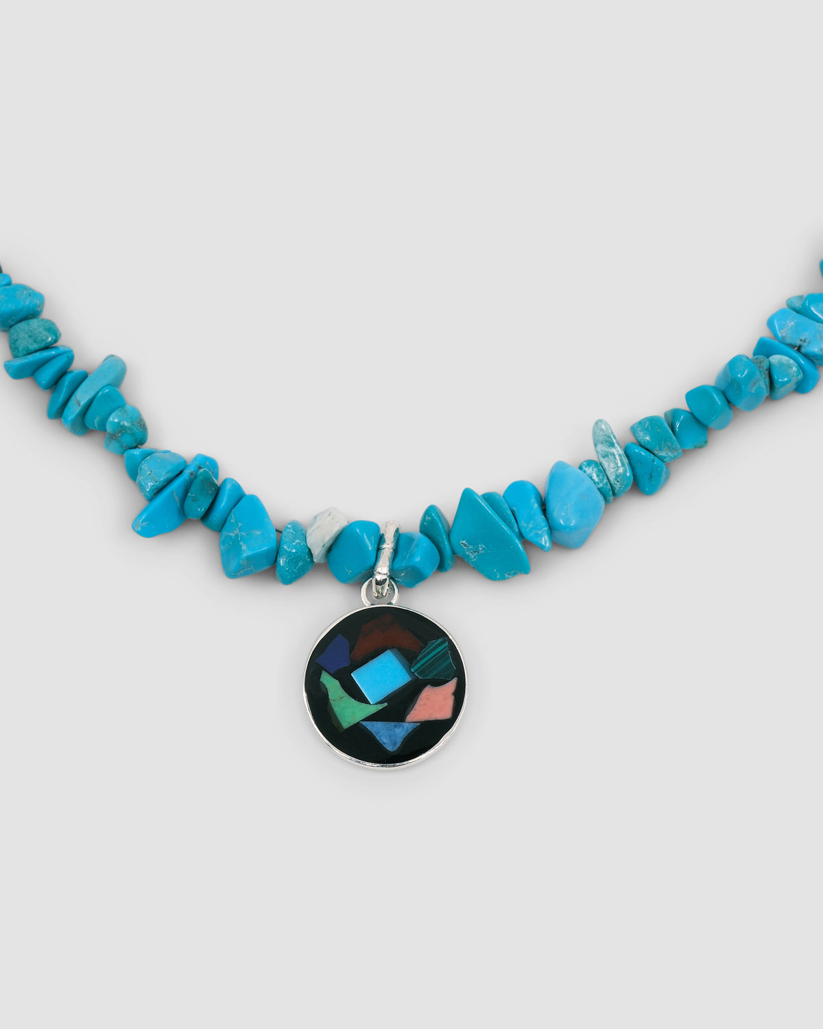 a turquoise jagged necklace with a central round multi colour and silver pendant