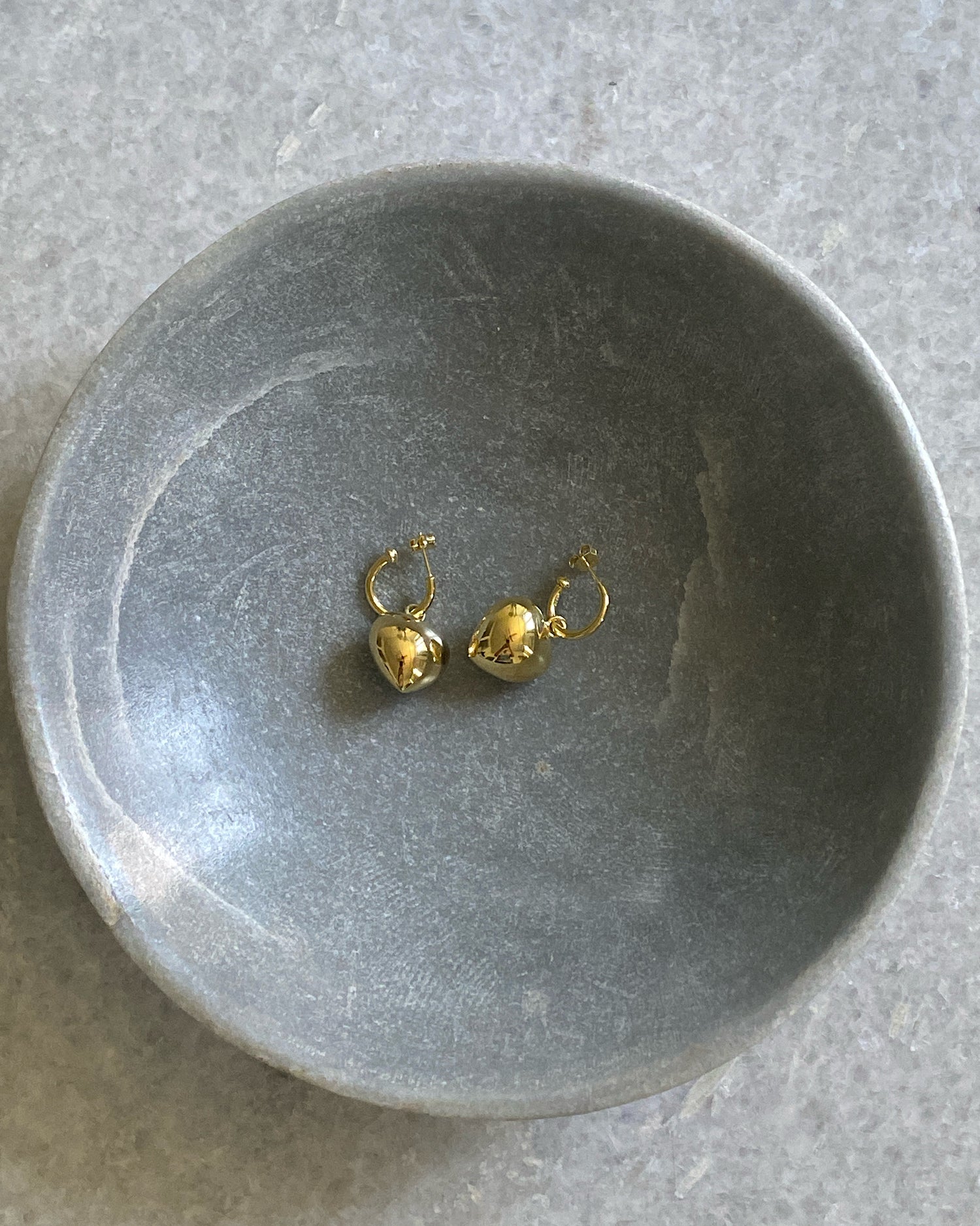 small heart earrings sit on a stone bowl