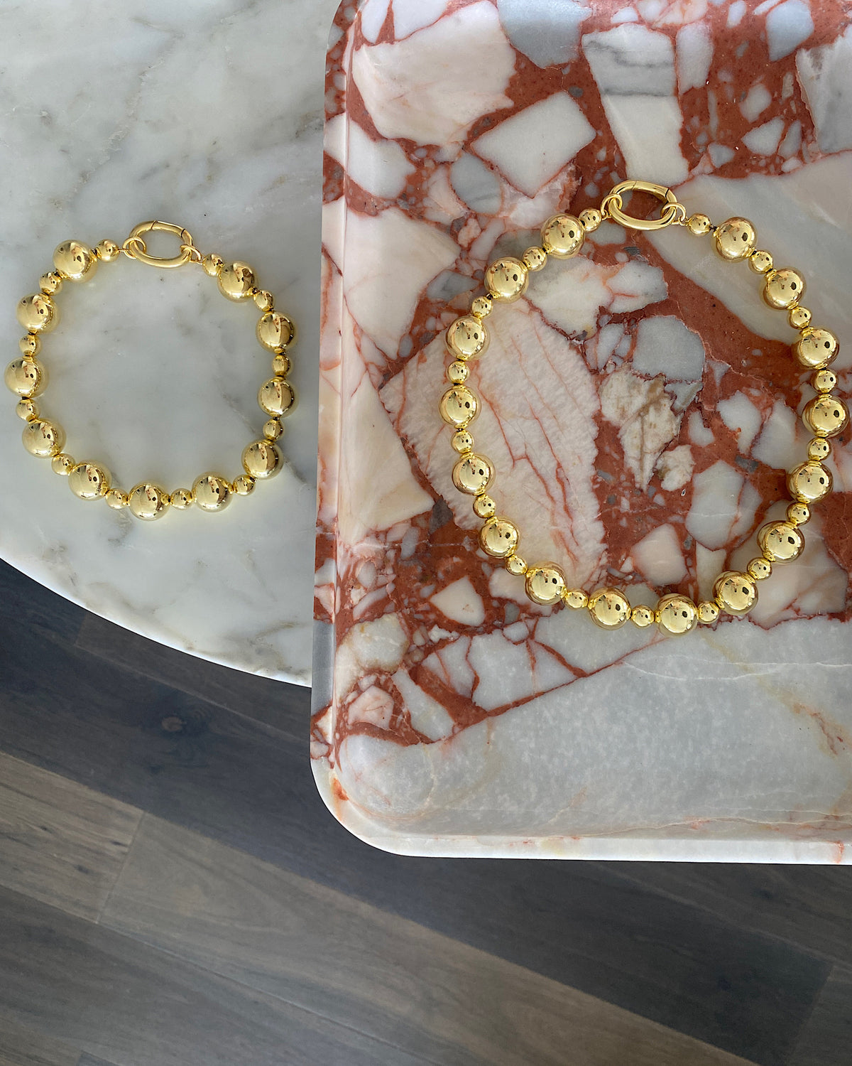 gold ball necklaces sit on marble