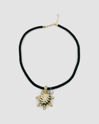 unusual striped gold pendant with pearls dotted around sit on a black cord pendant with a crystal