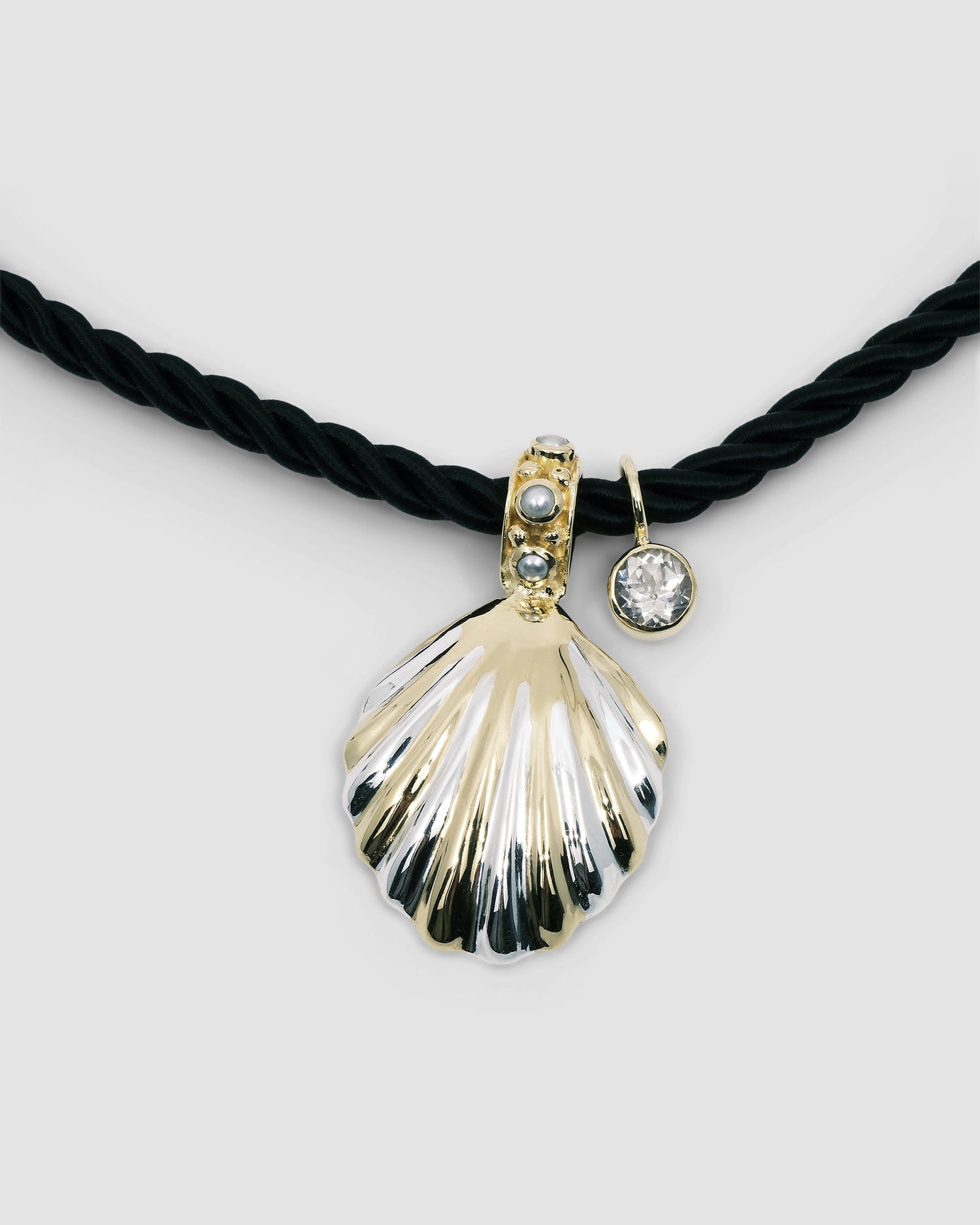 unusual striped gold shell pendant with pearls dotted around sit on a black cord pendant with a crystal