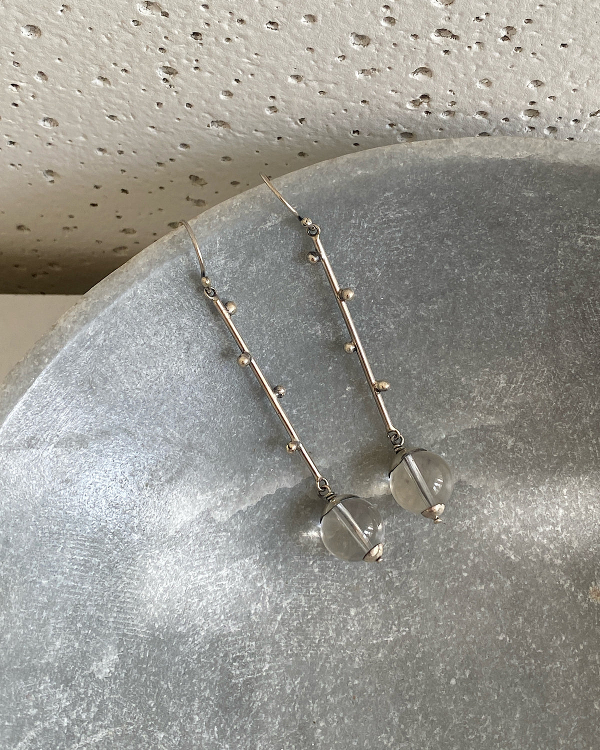 long silver drop earrings sit oin a marble bowl