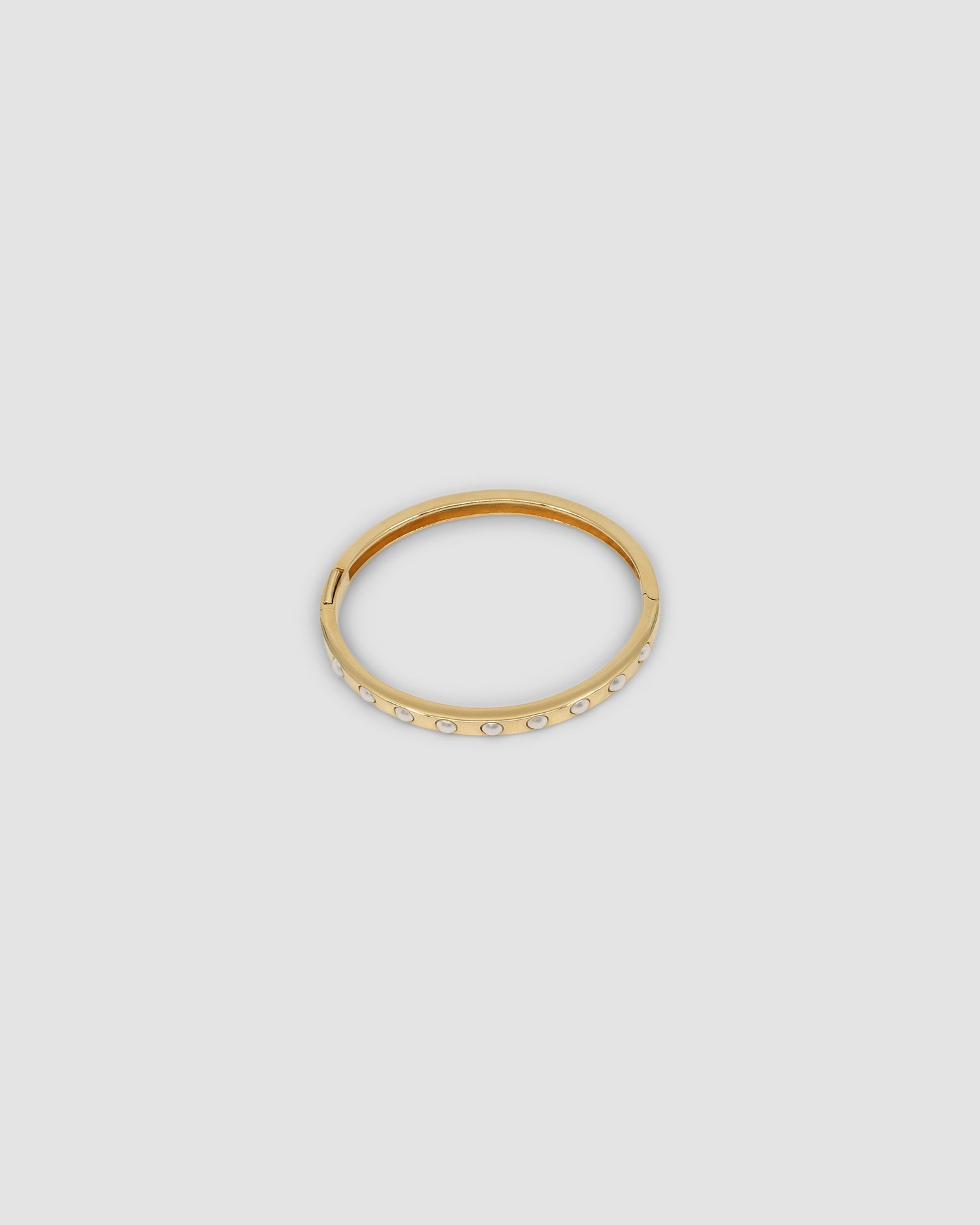 Gold bangle featuring inlaid pearls