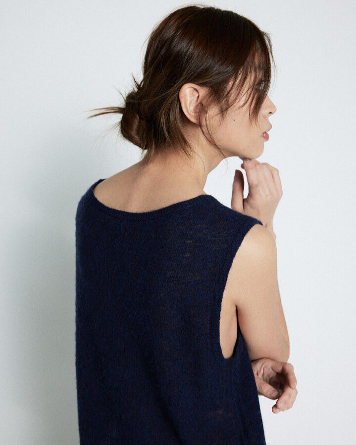 Woman wearing a navy blue sleeveless top against a white background