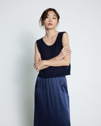 Woman wearing a navy blue sleeveless top and skirt against a light gray background