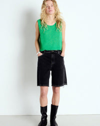 Woman wearing a green sleeveless top from American Vintage and black shorts against a white background at The Pared Store