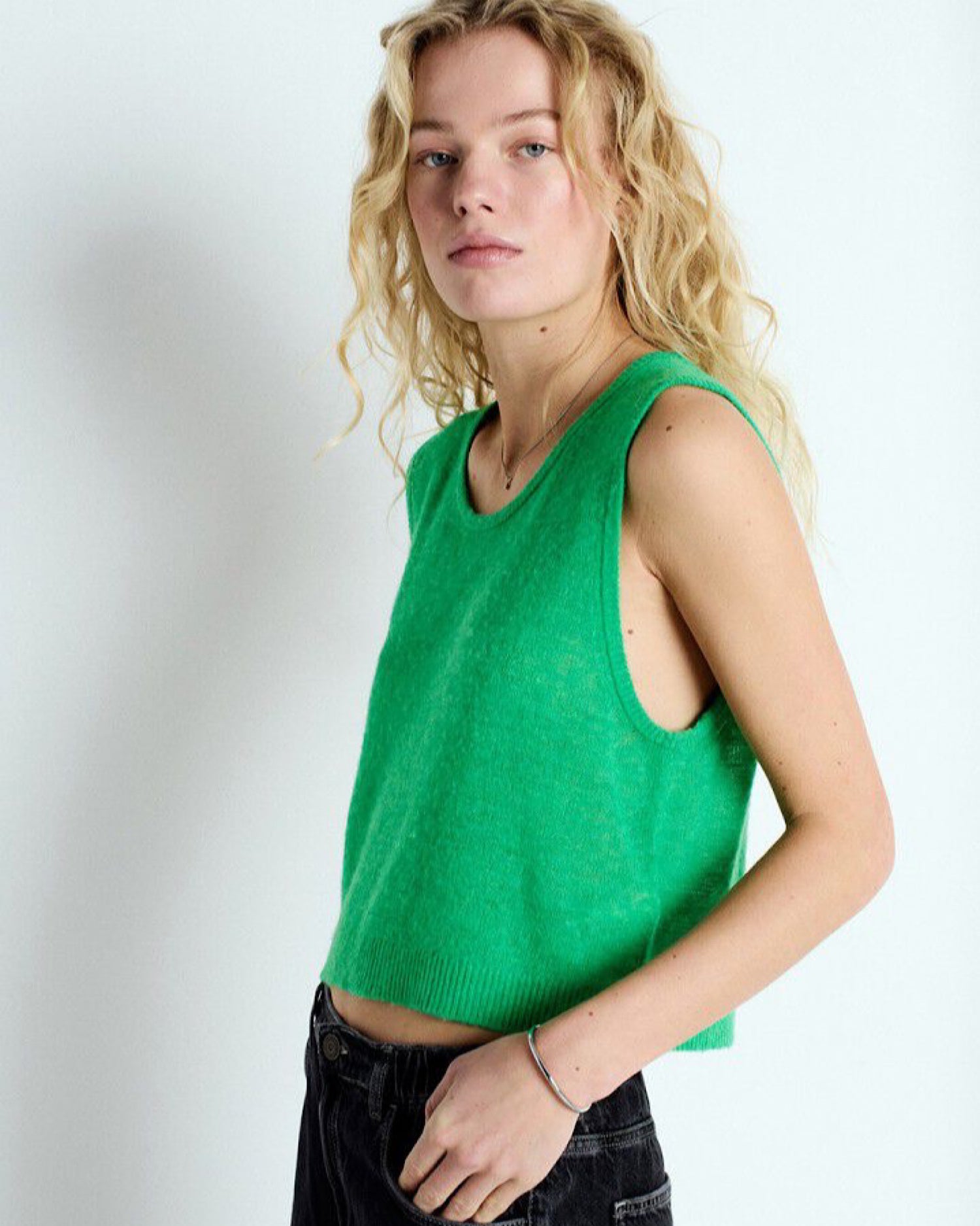 Woman wearing a green sleeveless top by american vintage against a white background