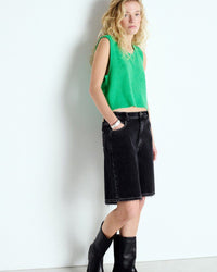 Person wearing a green sleeveless top and black shorts against a white background available at The Pared Store