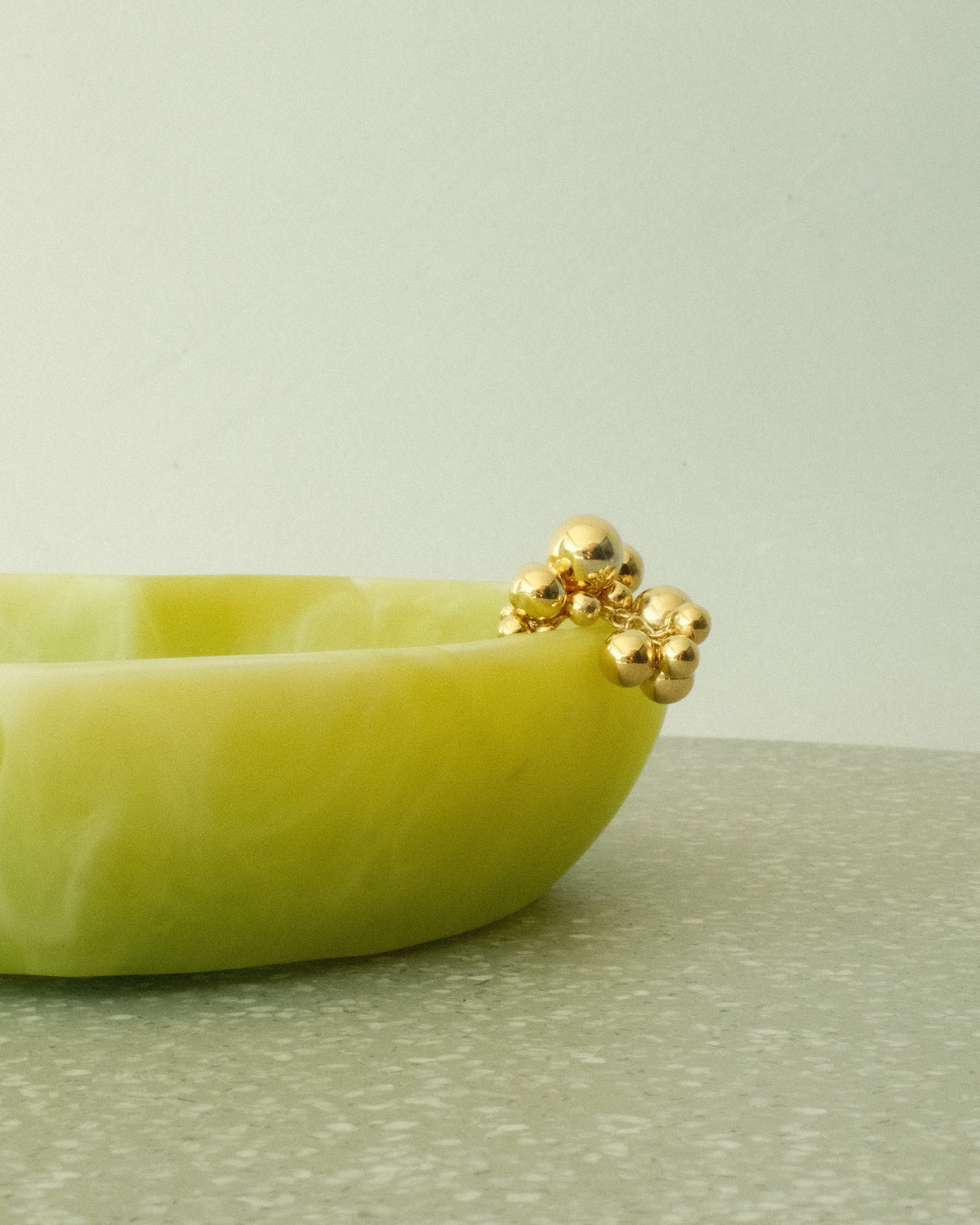 a gold bubble ring rests on a green bowl