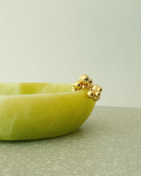 a gold bubble ring rests on a green bowl