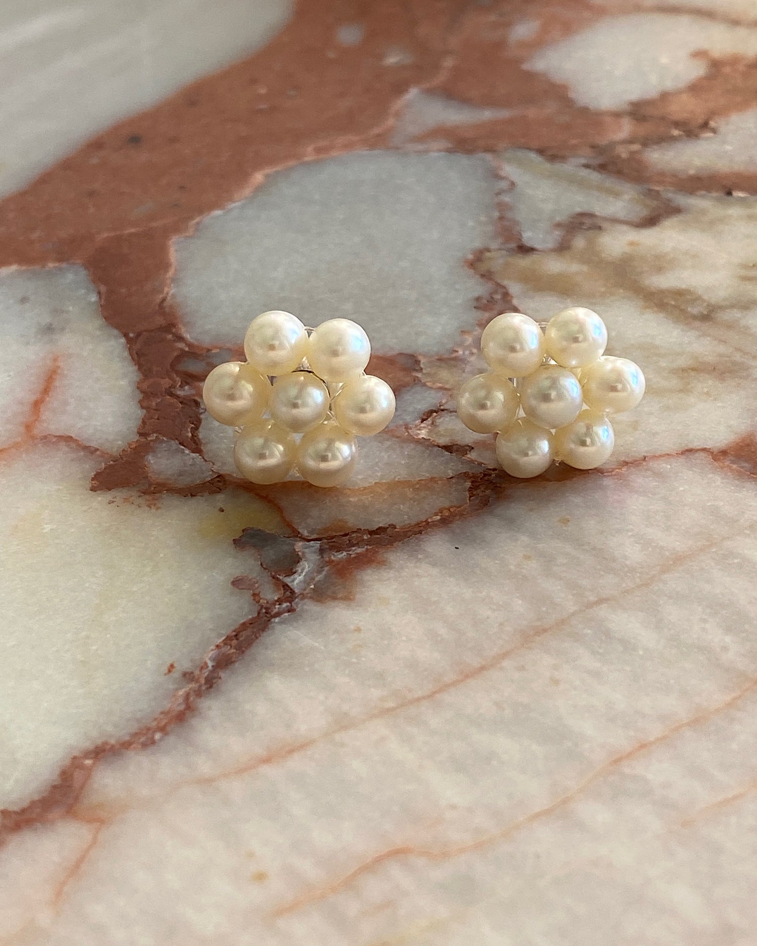 small pearl flower stud earrings sit on marble