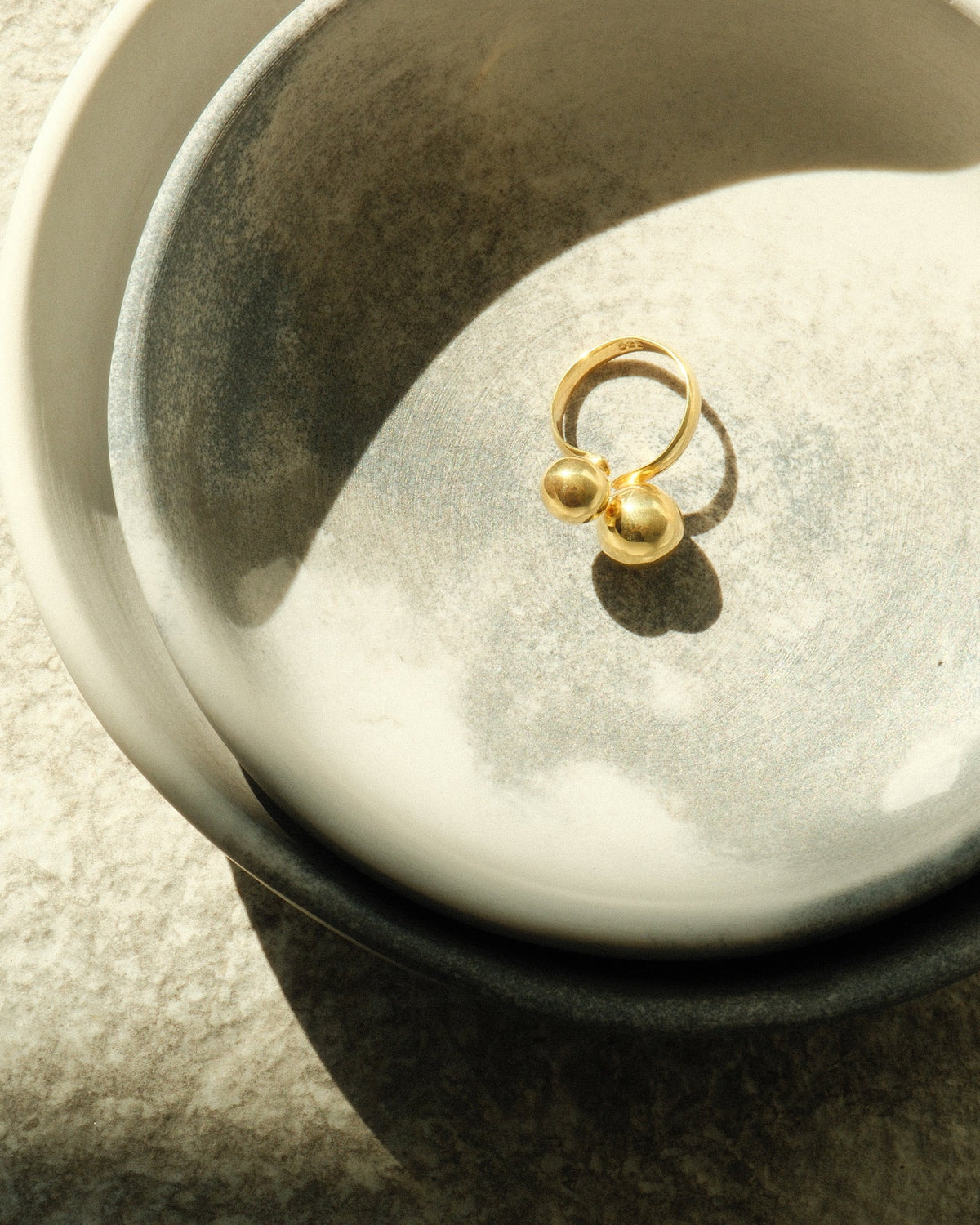 double ended double bubble gold ring sits in a bowl