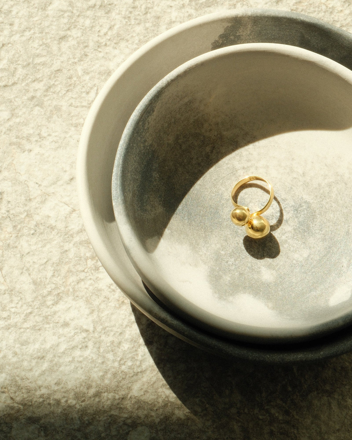 double ended double bubble gold ring sits in ceramic bowls