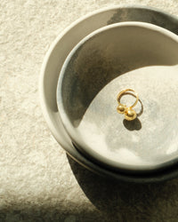 double ended double bubble gold ring sits in ceramic bowls