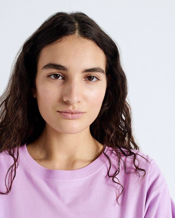Person wearing a light purple shirt against a white background
