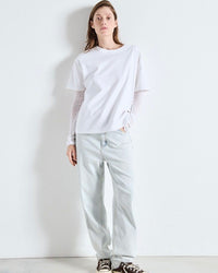 Person wearing an American Vintage  white t-shirt and light gray pants against a white background
