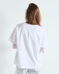Person wearing a plain white t-shirt against a light gray background