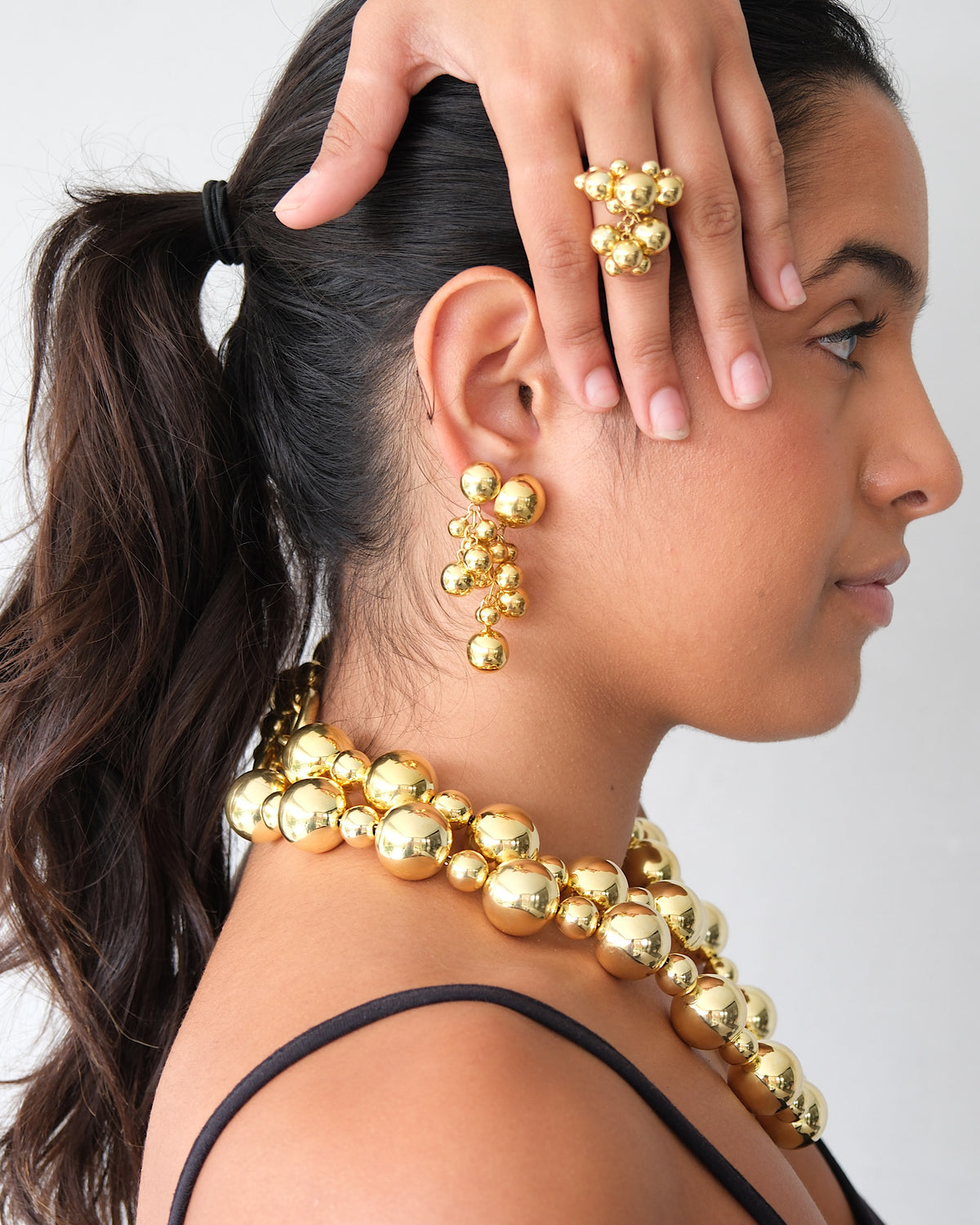 a model; wears small and large bubble earrings with bubble necklaces and ring