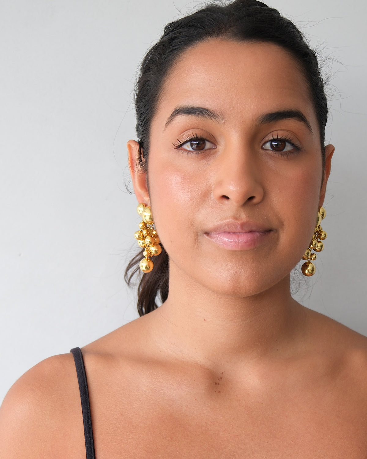 model wears large and small ball earrings