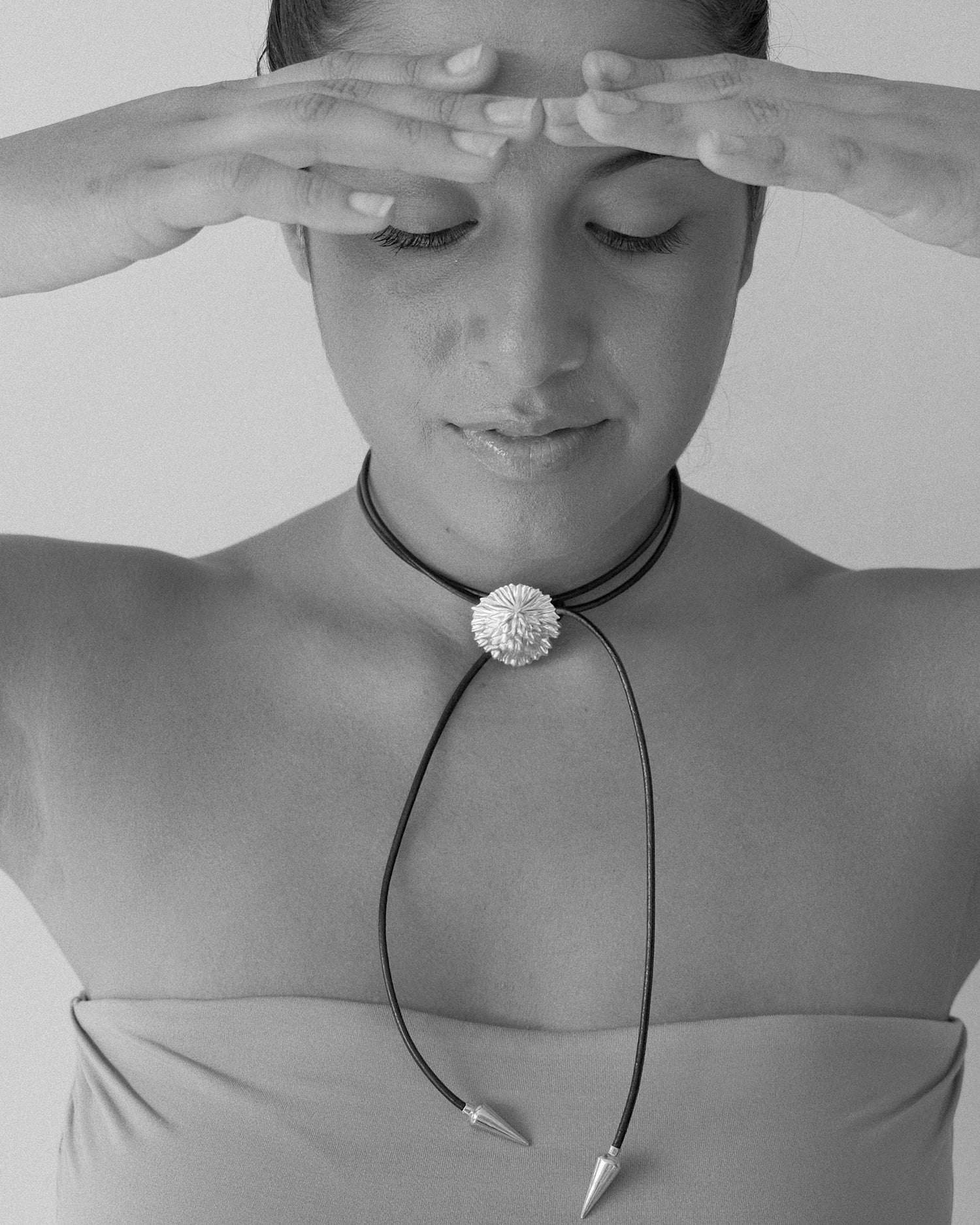 model wears leather cord necklace with pointed ends and a flower charm