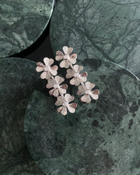 Silver flower & moonstone drop earrings rest on green marble