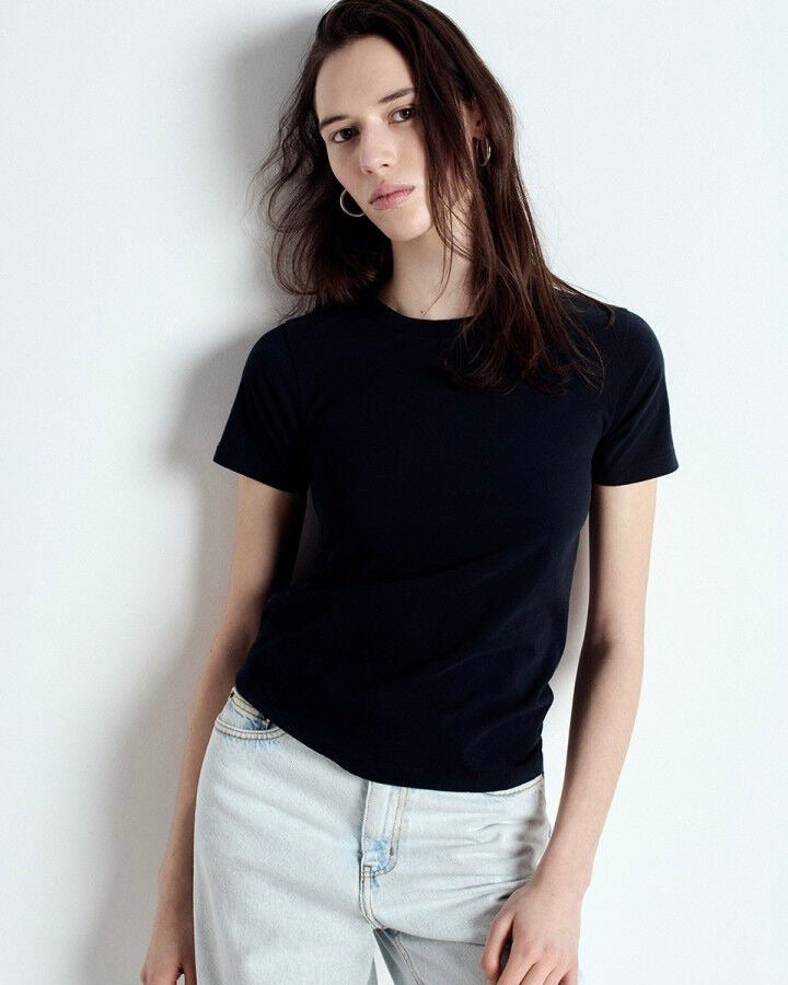 Woman wearing a black t-shirt and light blue jeans against a white background