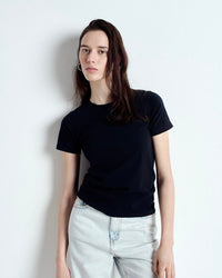 Person wearing a black t-shirt and light blue jeans against a white background