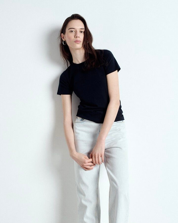 Person wearing a black t-shirt and white pants against a light gray background