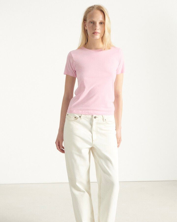 Person wearing a pink t-shirt and white pants on a white background