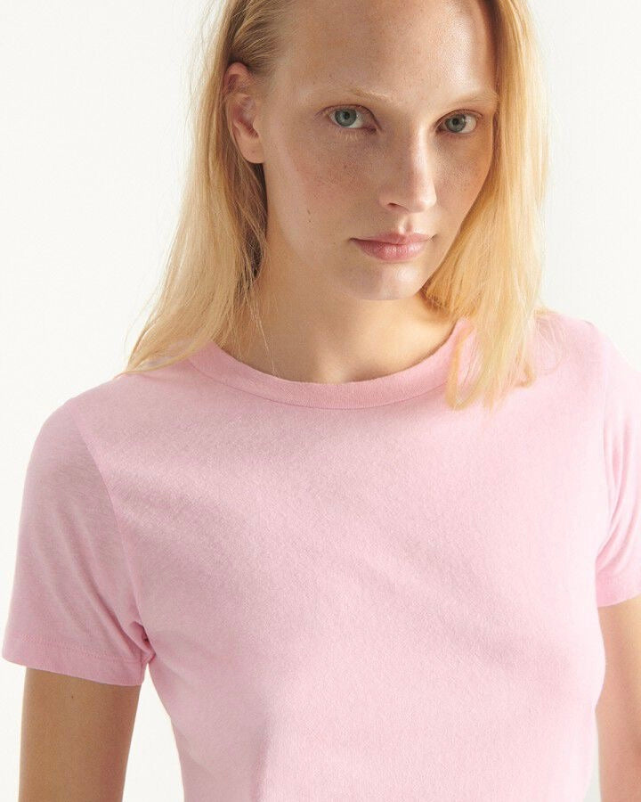 Person wearing a plain pink t-shirt against a white background