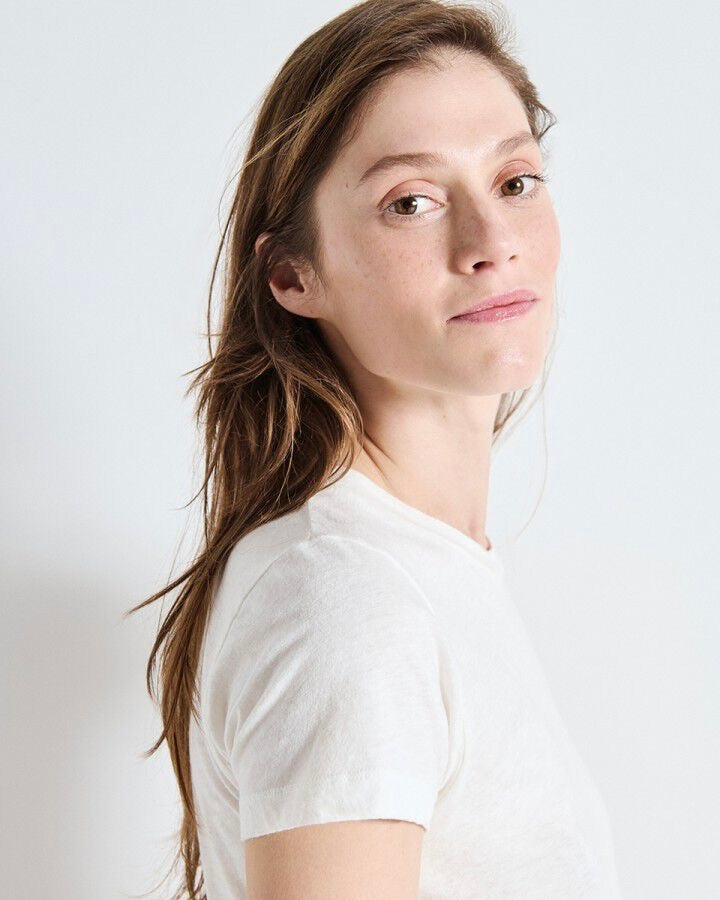 Woman wearing a white t-shirt against a plain background