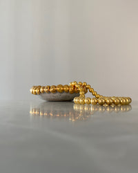 gold ball necklace on a marble background