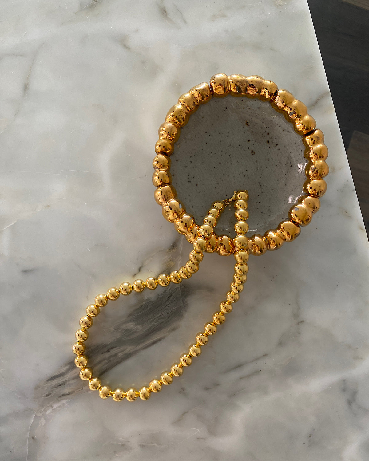 gold ball necklace on a marble background