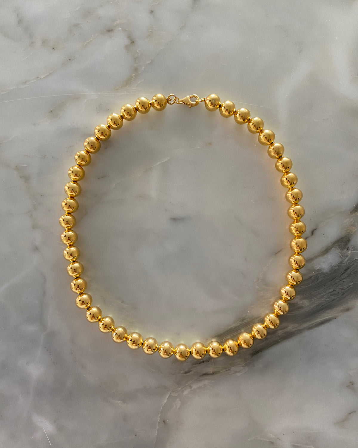 gold ball necklace on a marble background