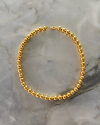 gold ball necklace on a marble background