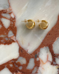 wide gold hoop earrings on marble