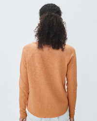 Person wearing a brown orange sweater from American Vintage on a plain background