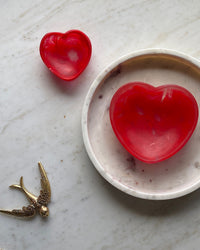 two red resin heart bowls, a marble tray and a brass swallow