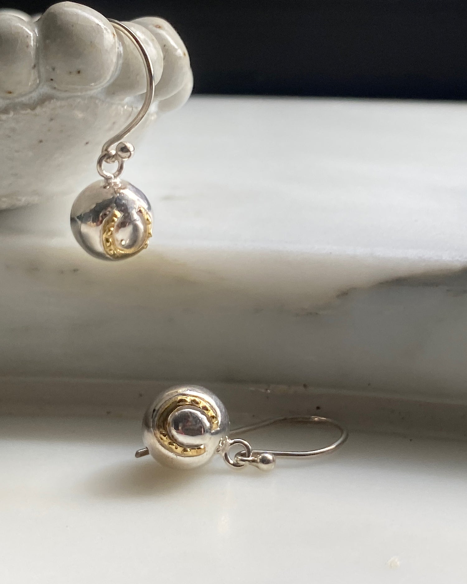 Silver ball drop earrings with a hook featuring a gold horse shoe